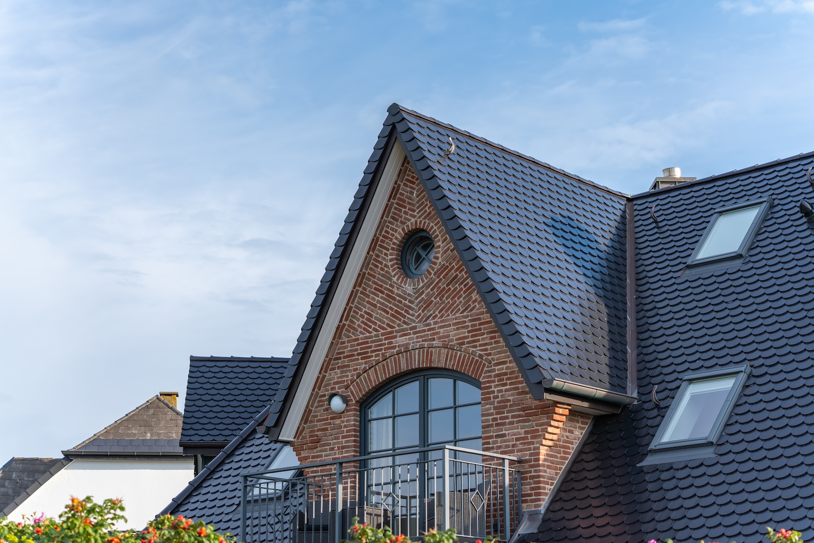 Modern brick house with slate roof. A modern brick house features a steep slate roof and arched windows.