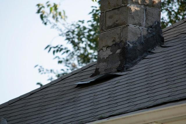 Flashing around a chimney and the surrounding shingles are morphed and no longer level against the rest of the roof.