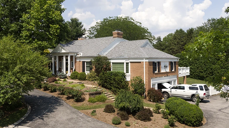 A brick house with grey shingle roofing